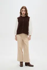 Chaleco de punto texturizado en color marrón chocolate, con cuello redondo y cierre frontal de botones a tono.