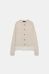 Chaqueta de punto color beige con cuello redondo, manga larga y cierre frontal con botones. Presenta un diseño combinado con volados de tela en el bajo.