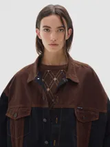 Campera tipo trucker de corte oversize, confeccionada en algodón con diseño colorblock en tonos azul marino y bordó. Presenta cierre frontal con botones metálicos, cuello clásico y bolsillos frontales con solapa.