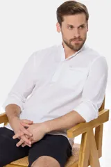 Camisa blanca de lino y algodón, de corte slim, con cuello mao, medio abotonada y manga larga. Tiene un bolsillo en el pecho.