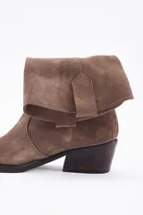 Bota corta estilo western confeccionada en cuero descarne color marrón, con taco cuadrado de madera y punta ligeramente afinada.