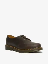 Zapato de tres ojales Dr. Martens modelo 1461, confeccionado en cuero Crazy Horse de color marrón con acabado encerado. Presenta costuras amarillas visibles en el borde de la suela y suela de goma con cámara de aire.
