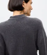 Suéter de punto color marrón chocolate, con cuello alto y mangas largas con puños ajustados. Presenta un diseño de corte corto y holgado.