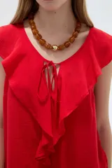 Blusa negra de viscosa sin mangas, con cuello redondo, volados frontales y detalle de lazo en el escote.