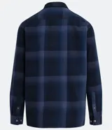 Camisa de manga larga con diseño de cuadros en tonos marrones, confeccionada en algodón. Presenta cuello camisero, cierre frontal con botones y un bolsillo en el pecho con botón.