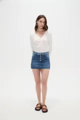 Minifalda de jean azul con cierre frontal de botones metálicos y detalles de estampado animal print en la pretina y los bolsillos superiores. Cuenta con un dobladillo desmechado.