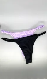 Pack de dos bombachas tipo colaless de algodón, una en color negro y otra en lila, con tiras laterales fruncidas elásticas.