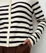 Cardigan de punto corto con diseño de rayas horizontales, cuello redondo, cierre frontal con botones y mangas largas con puños acanalados.