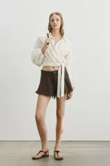 Short de cinco bolsillos en denim de algodón rígido, de tiro alto con cierre y botón, corte holgado y bajo deshilachado.