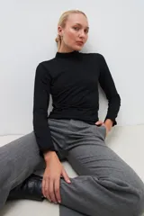 Remera negra de manga larga con cuello alto y volados en los puños.