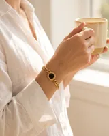 Pulsera de cadena de eslabones con baño de oro y dije circular central con piedra ónix negra.