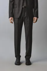 Pantalón de traje de corte regular fit confeccionado en lana de origen italiano. Presenta un diseño de cuadros sutiles, bolsillos laterales, bolsillos traseros de doble vivo con botón y cierre frontal con cremallera y botón.