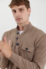 Sweater azul con cuello alto abotonado y dos bolsillos frontales con botón.