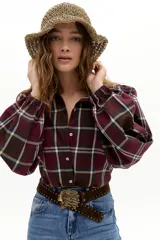 Camisa de algodón con estampado de cuadros en tonos bordó, verde y beige. Presenta mangas largas abullonadas con puños fruncidos, cuello camisero clásico y botones de nácar.