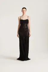 Vestido largo negro de encaje transparente, con tirantes finos, escote recto y botonadura frontal.