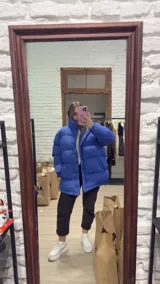 Campera puffer de corte oversize en color azul vibrante, con cuello alto, cierre frontal y botones a presión. Presenta un diseño acolchado con costuras horizontales y bolsillos laterales.