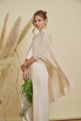 Capa de gasa color beige con cuello alto y diseño cruzado en el frente, de corte fluido y elegante.