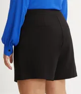 Bermuda de crepé color blanco, de corte holgado y tiro alto, con pliegues frontales y bolsillos laterales con detalle de botones. Confeccionada en poliéster y elastano.