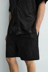 Bermuda de corte regular confeccionada en tejido fluido con textura jacquard geométrica. Presenta cintura elástica con cordón ajustable, bolsillos laterales y bolsillos traseros de vivo.