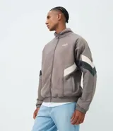 Buzo de fleece con cierre frontal completo y cuello alto. Presenta un diseño con recortes en tonos blanco y negro en las mangas y laterales, y cuenta con una estampa pequeña en el pecho.