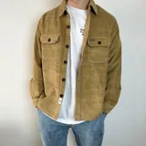 Sobrecamisa de pana en color tostado, con cierre frontal de botones, cuello clásico y dos bolsillos frontales con solapa y botón.