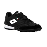 Championes de fútbol Lotto color negro con detalles en blanco. Presentan el logo de la marca en el lateral y una pequeña bandera italiana decorativa. Cuentan con suela apta para césped sintético.