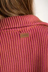 Campera tejida de algodón con diseño acanalado, cuello alto y cierre frontal completo. Presenta un patrón bicolor en tonos terracota y rosado, con puños y cintura elásticos.
