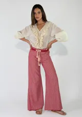 Pantalón de lino a rayas rojas y blancas, de corte ancho y tiro medio, con cintura elástica ajustable mediante cordón.