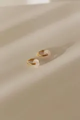 Aros de acero quirúrgico dorados en forma de argolla con dijes de piedra natural negra en forma de dona, desmontables.
