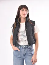 Chaleco negro con cuello alto y cierre frontal con botones a presión.