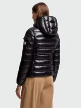 Campera puffer corta de nylon laqué color negro, con relleno de plumas, capucha desmontable, cierre frontal con cremallera y bolsillos laterales con cremallera.