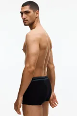 Pack de tres calzoncillos tipo trunk de algodón con elastano, de color negro con cinturas elásticas de diferentes colores: verde oscuro, beige y marrón. Cuentan con costuras planas y parte delantera forrada.