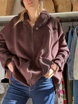 Campera con capucha de diseño oversize, confeccionada en tejido tipo paño color chocolate, con cierre frontal completo y puños de tejido acanalado a tono.