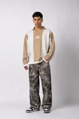 Sweater de tejido de punto con diseño de rayas verticales en tonos beige y blanco. Presenta cuello polo abierto, mangas largas y un corte holgado. Incluye un logo bordado en el centro del pecho.