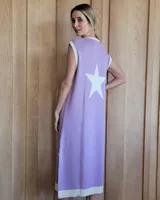 Vestido largo color lila, sin mangas, con cuello redondo y una gran estrella blanca estampada en la espalda. El cuello y el dobladillo inferior son de color beige.