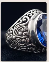 Anillo de plata 925 con diseño calado y piedra facetada azul en forma ovalada.