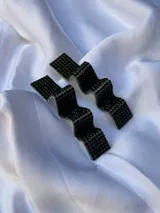 Par de aros colgantes con forma geométrica irregular, recubiertos de strass negros sobre base plateada.