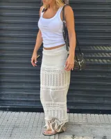 Falda larga de tejido calado color blanco crudo, con detalle de flecos en el dobladillo.