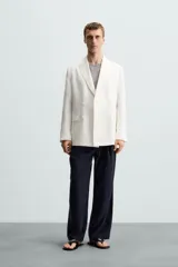 Blazer color crudo de lino y algodón, corte regular, con cuello de solapa de pico, manga larga con puños abotonados, bolsillos de vivo en el pecho y bolsillos de solapa en la cadera, bolsillo interior, aberturas en la espalda y cierre frontal cruzado con botones.