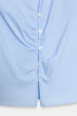 Camisa de color celeste con cuello solapa, escote en pico y manga corta. Presenta un diseño entallado con detalle de frunces verticales en la parte central y cierre frontal con botones.