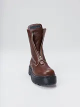 Botas de cuero color marrón de caña alta, con plataforma gruesa de goma y cierre metálico frontal con tirador. Presentan costuras a contratono y detalle de etiqueta de la marca en la lengüeta.