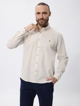 Camisa de manga larga con estampado de cuadros finos, cuello clásico con botones y cierre frontal. Presenta un bordado pequeño en la pechera y puños abotonados.