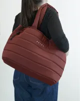 Bolso tipo tote bag acolchado color bordó, con asas de hombro tubulares y logo estampado en el frente.