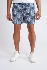 Short de baño con cintura elástica y cordón ajustable, confeccionado en tela ligera de secado rápido. Presenta un estampado botánico integral en tonos amarillos, blancos y azules, con dos bolsillos delanteros y uno posterior.
