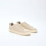 Zapatillas bajas color beige con textura, cordones y detalle marrón en el talón.