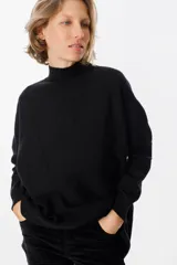 Sweater de punto negro con cuello alto y diseño de espiga calada que recorre el frente. Presenta mangas largas con puños acanalados y un corte holgado.