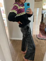 Sweater negro con diseño geométrico en blanco, rosa y amarillo en la parte superior.