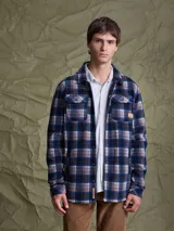 Sobrecamisa de tejido polar con estampado abstracto en tonos rojizos y azul marino. Presenta cuello clásico, cierre frontal con botones a presión, dos bolsillos frontales con solapa en el pecho y un parche decorativo.