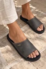 Sandalias tipo chinela Clog Dune de cuero gastado color gris oscuro, con suela plana y mini plataforma. Presenta detalle de iniciales VDM doradas en el lateral.