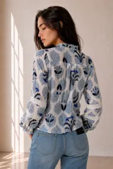 Camisa de manga larga con estampado floral en tonos azules y blancos, cuello con volados y detalles de encaje a lo largo de la botonadura y en las mangas.
